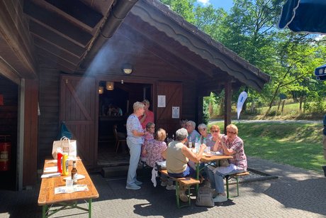Personen an einem Tisch vor einer Grillh&uuml;tte