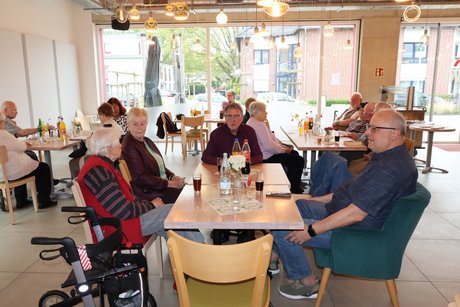 Mehrere Menschen sitzen am Tisch.