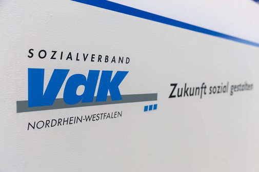 Weiße Wand mit blauem Logo des VdK-NRW und Slogan: Zukunft sozial gestalten