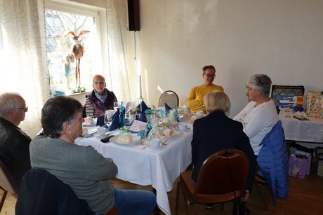 Mehrere Menschen sitzen an gedeckten Tischen.