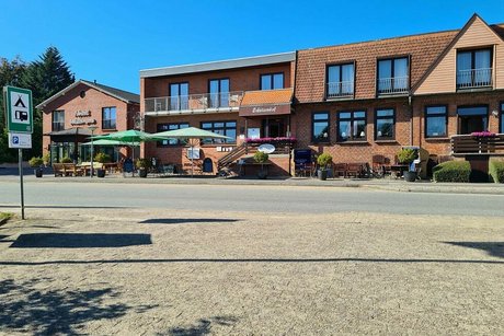 Außenfassade des Hotel Schützenhof mit grünen Sonnenschirmen auf der Außenterrasse.