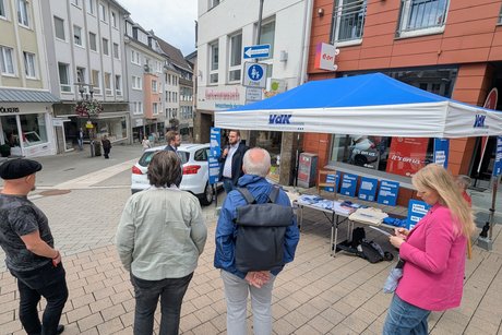Menschen stehen vor dem VdK-Stand zur Kommunalwahl in Siegen.