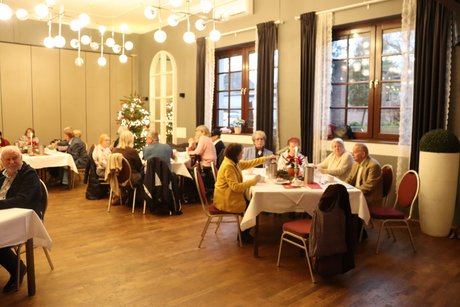 Mehrere Menschen sitzen an festlich gedeckten Tischen.