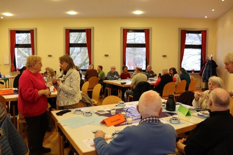 Jahreshauptversammlung - mehrere Personen stehen oder sitzen an Tischen und unterhalten sich miteinander.