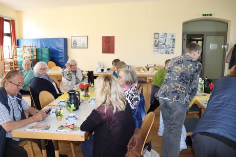 Treffen der Vertreterinnen der Frauen im Mehrgenerationenhaus. Menschen sitzen an langen Tischen und unterhalten sich miteinander.