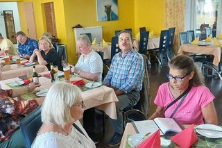 Menschen sitzen gemeinsam an Tischen im Restaurant der Straußenfarm.