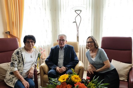 Zwei Frauen und zwischen ihnen sitzt ein Mann der seinen 90. Geburtstag feiert.