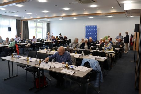 Viele Delegierte sitzen an langen Tischen.