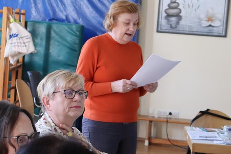 Treffen der Vertreterinnen der Frauen im Mehrgenerationenhaus. Eine Frau steht und liest etwas von einem Zettel ab.