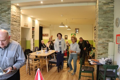 Mitglieder kommen zum Buffet. Mehrere Personen gehen zum Buffet und andere sitzen noch an ihren Tischen.