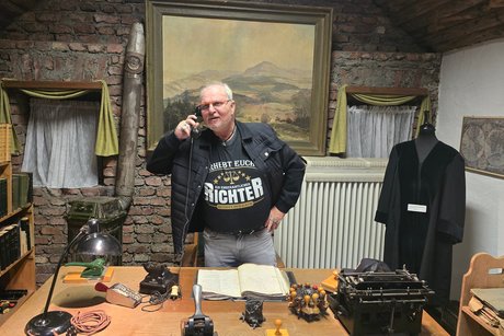 Amtszimmer eines Richters im 19. Jahrhundert - Gerichts-Museum Bad Fredeburg mit dem Autor und Ehrenrichter P.R. Als moderner Richter mit T-Shirt auf dem steht: "Aufstehen Ein ehrenamtlicher Richter betritt den Raum.