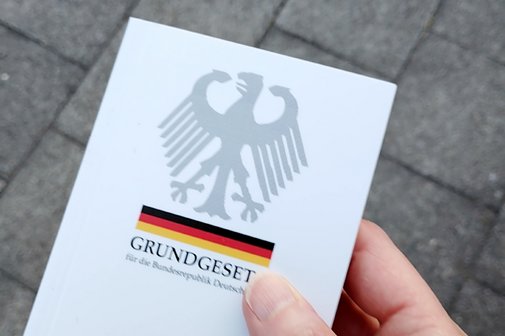 Wei&szlig;es Taschenbuch mit der Aufschrift Grundgesetz der Bundesrepublik Deutschland und Nationalfarben