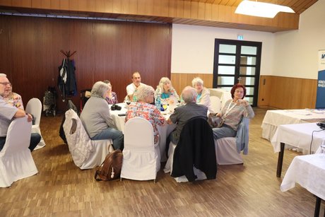 Mehrere Personen sitzen an einem runden Tisch.