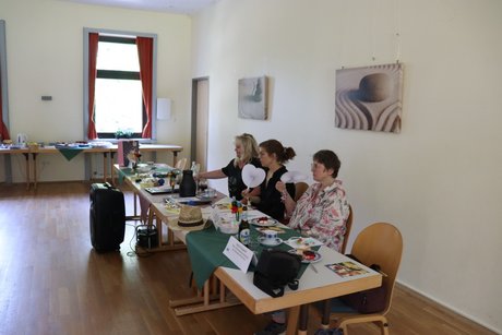 Treffen der Vertreterinnen der Frauen. 3 Frauen sitzen an 2 Tischen.