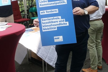 Vorstandsmitglied Michel Zwirner zeigt ein Plakat mit VdK Forderungen.