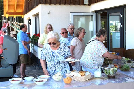 Mitglieder am Grillbuffet Mitglieder stehen am Grillbuffet