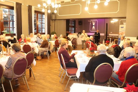 Mitglieder und G&auml;ste sitzen an festlich gedeckten Tischen.