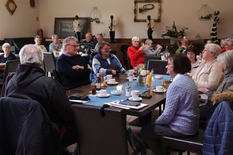 Frühlingsfest Mehrere Menschen sitzen an vier Tischen und unterhalten sich miteinander.