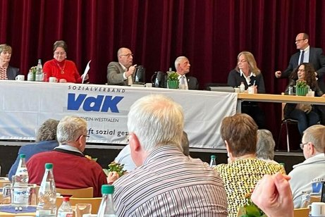 Sechs Menschen sitzen auf einer Bühne an einem Tisch vor Publikum
