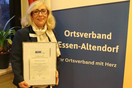 Eine Frau steht mit einer Urkunde in den H&auml;nden neben einem Rollup vom Ortsverband Altendorf.
