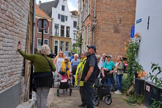 Interessiere Besucher beim Stadtrundgang stehen vor einer alten Ziegelmauer.