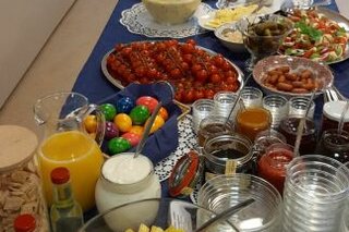 Buffettisch mit Hefezopf, Obstsalat, Cocktailtomaten, Rührei, Würstchen, Käsecreme, Aufschnitt, O-Saft, Marktkäse, Croissants, Saft und und und