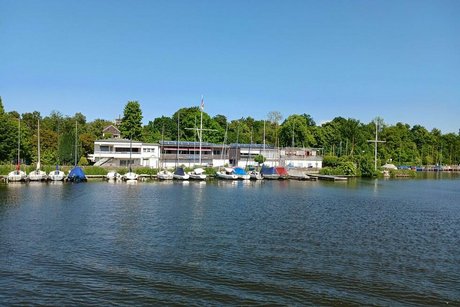Zahlreiche Segelboote liegen an einem Anleger am Ufer.