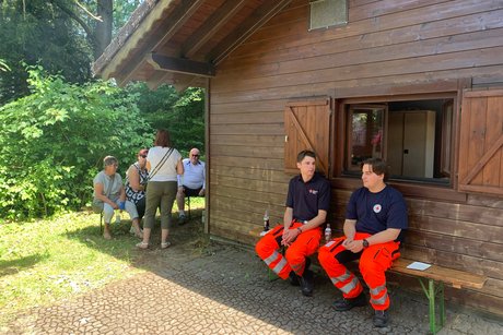 Personen und zwei Sanit&auml;ter vor einer Grillh&uuml;tte