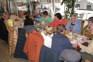 Viele Menschen sitzen gemeinsam beim Frühstück an einem langen Tisch.