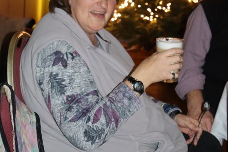 Eine Frau sitzt am Tisch und trinkt Kaffee.