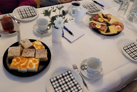Gedeckter Kaffeetisch mit je einem Teller Schnittchen und Kuchen.
