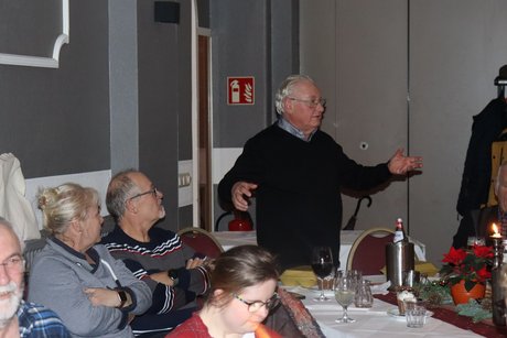 Ein Mann ist aufgestanden und spricht zu den Anwesenden.