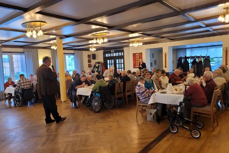 Klaus Meiers stehend begrüßte alle Anwesenden sitzend an den Tischen zum Infonachmittag.