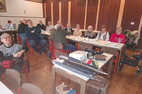 Schirmmacher Willy Schüffler hält einen Vortrag über seinen Beruf und die Geschichte des Schirms. Mehrere Mitglieder sitzen an langen Tischen und verfolgen den Vortrag.