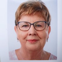 Frau mittleren Alters mit Brille, ein Lächeln im Gesicht und kurzes blondes Haar