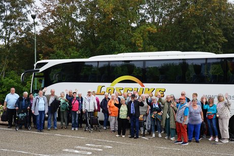 Mitglieder stehen vor Bus und winken