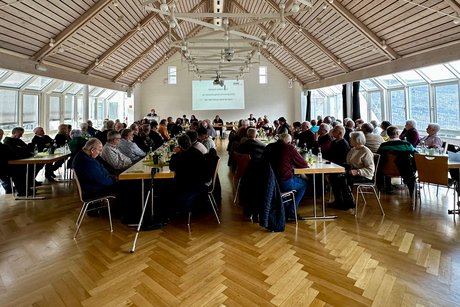 Saal mit Menschen an Tischen sitzend