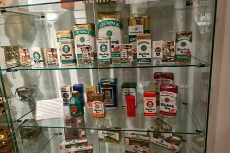 In einer Glasvitrine sind zahlreiche alte Teeverpackungen von Bünting ausgestellt.