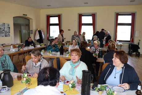 Treffen der Vertreterinnen der Frauen im Mehrgenerationenhaus. An mehreren langen Tischen sitzen vor allem Frauen und unterhalten sich miteinander.