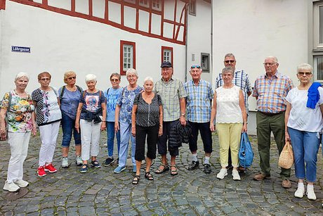 Gruppenfoto der Reisegruppe vor einem weißverputzen Haus mit roten Fachwerkbalken.