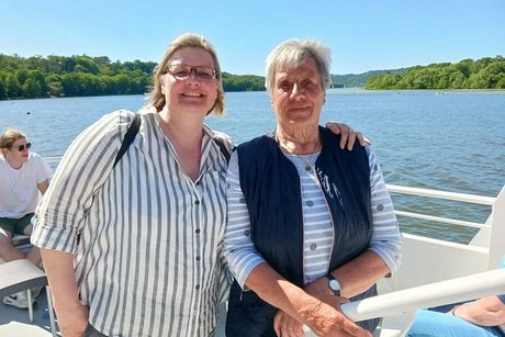 Zwei Frauen stehen nebeneinander am Außendeck des Ausflugsschiffs in der Sonne.