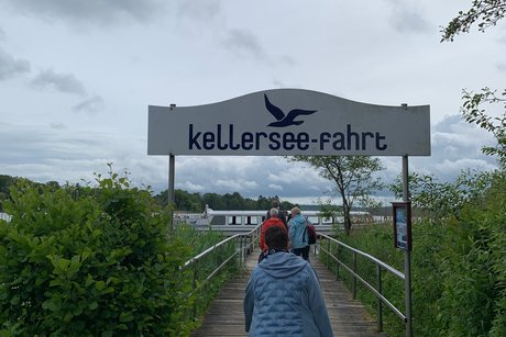 Schifffahrt Kellersee Menschen auf einem Steg in Richtung Schiff gehend