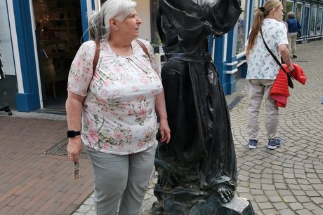 Eine Frau steht neben einer Metallfigur.