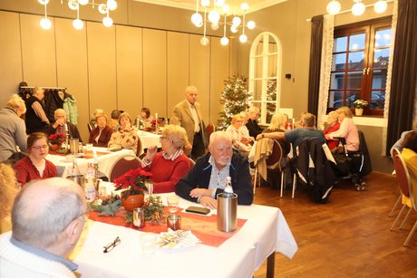 Mehrere Menschen sitzen an festlich gedeckten Tischen.