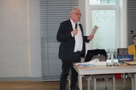Ein Mann spricht in ein Mikrophone und liest von einem Blatt ab.