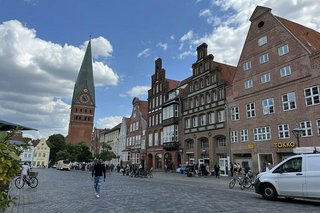 Alte Giebelhäuser und ein großer Kirchturm in der Altstadt von Lüneburg.