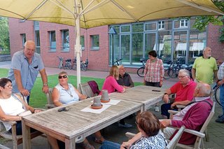 Ca. 10 Personen sitzen und stehen draußen beim Café Haus Hall