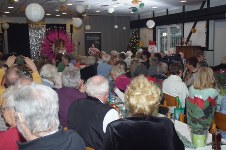 Teilnehmer Mitglieder und Gäste sitzen an Tischen, sie schauen der Show zu.