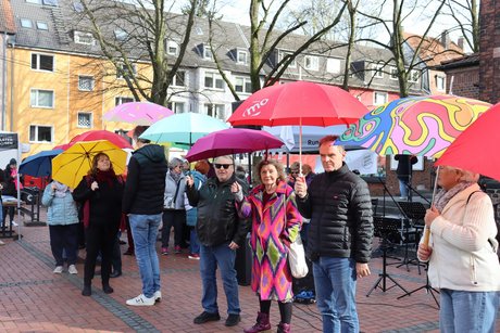 Auftaktveranstaltung internationale Wochen gegen Rassismus in Essen Holsterhausen. Viele Menschen stehen mit bunten Schirmen nebeneinander.