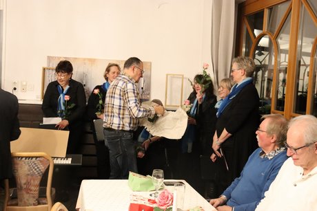 Ein Mann verteilt einzelne Rosen an die Damen des Chors.